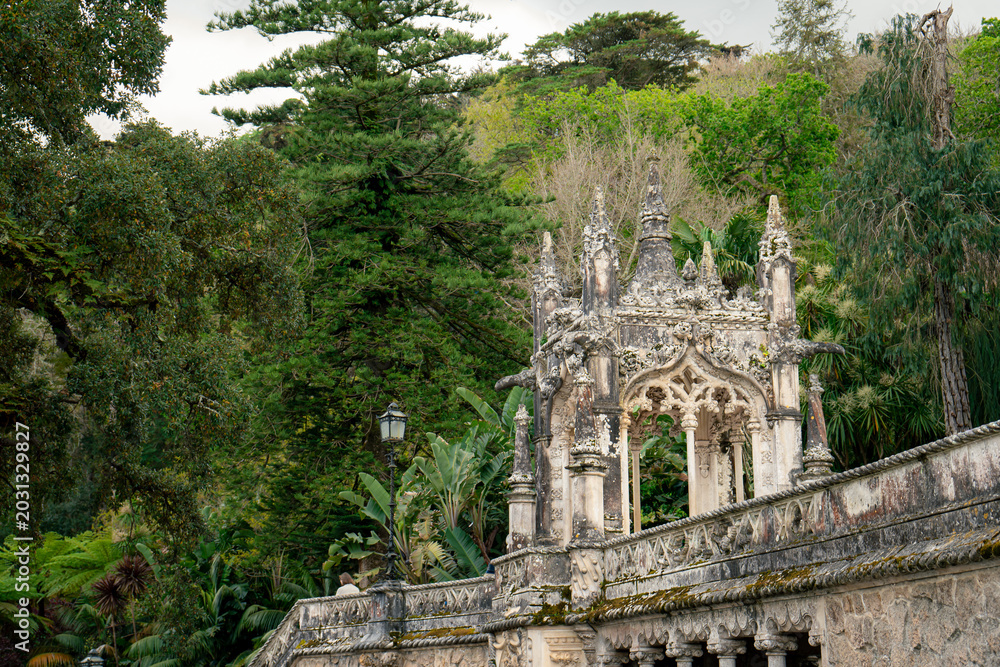 Fototapeta premium Intricate Stone Archway and Balustrade in a Lush Green Garden Environment. Quinta da Regaleira, Sintra, Portugal