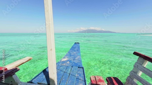 Front bow view of a moving motorized vessel cruising through ocean waters approaching a scenic coastal shoreline.