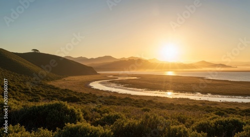 Golden hour illuminates coastal landscape with winding water and hills