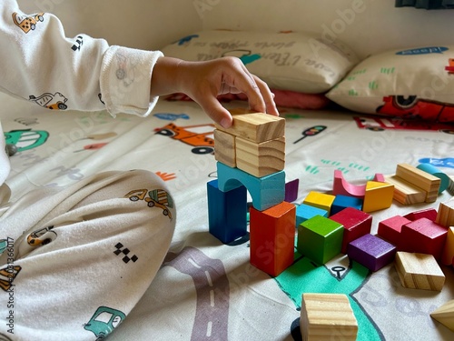 Canvastavla A child's hand is playing with a puzzle and colorful wooden blocks, to hone crea
