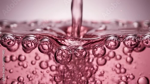 Closeup of pink liquid with rising bubbles and splash.