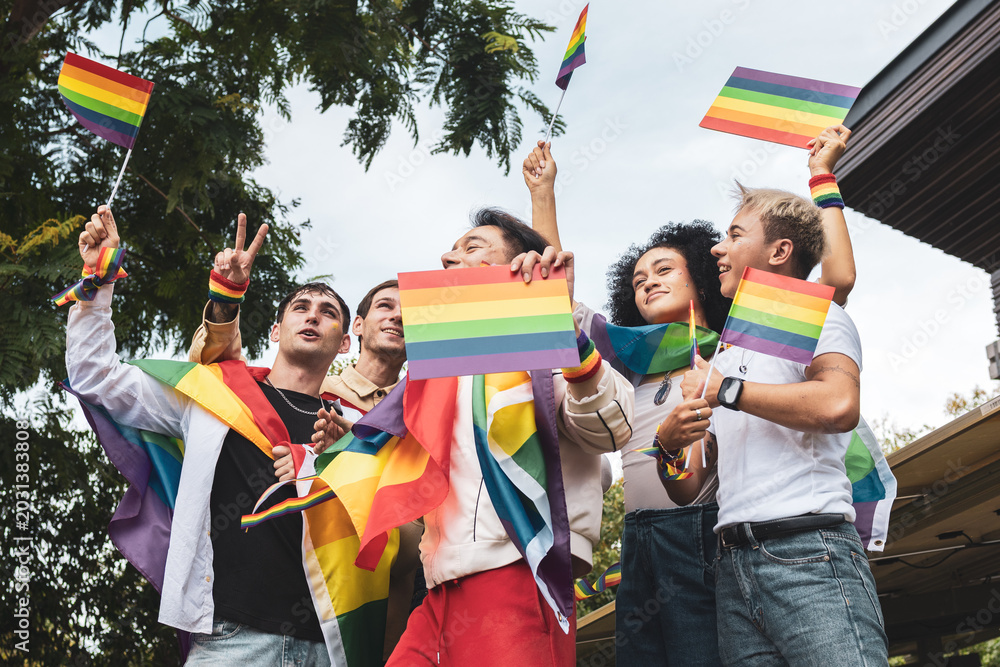 Obraz premium Pride month. Friends from IGBTQ, men, women, lesbians, and transgender people of various nationalities joined the parade in park, carrying signs and flags celebrating equal rights at Pride Festival. 