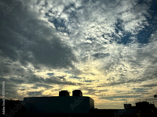 Warm Golden Evening Sky with Dark Rooftop Silhouette and Clouds