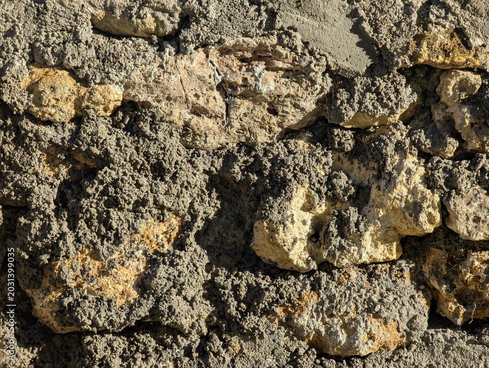 Fototapeta premium Rustic Stone Wall Texture with Rough Gray Mortar and Limestone Blocks Description: Close-up of an old, weathered stone wall built with irregular limestone blocks and thick, coarse gray mortar, showcas
