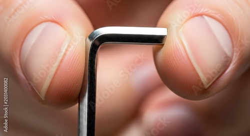 Close up of a hand holding a metallic hex key tool for furniture assembly