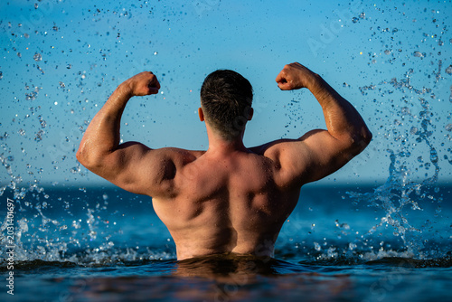 Obraz na plátně Summer ocean swimmer raises strong arms