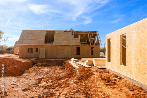 Workers on building new homes with wooden beams frames trusses framing materials in rural site.