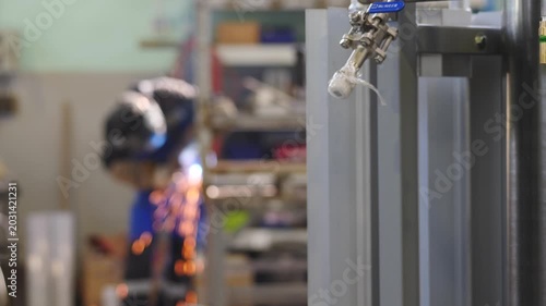 Blurred welder at work shot through crane beam remote control. Industrial settings. factory assembly line with worker in helmet, Metalworking sparks flying, welder working on steel box beam. 4k video