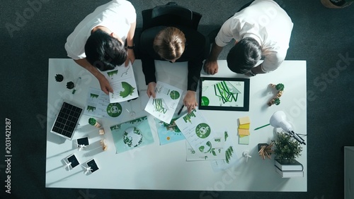 Top down view of business team discussing about renewable energy. Aerial view of skilled diverse business people working together to plan about zero waste while using laptop on table. Alimentation.