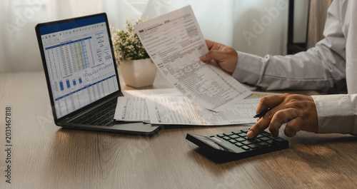 Tableau sur toile Accountant reviewing financial report and tax documents on laptop while using calculator for account analysis, real estate investment planning, expense management, and reporting workflow