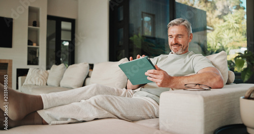 Fotografie Streaming, relax and man on couch with tablet, movie binge and video watching on digital app