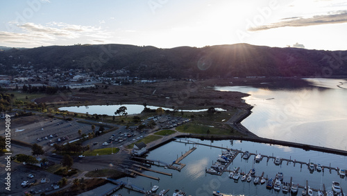 Foto Waterfront Park marina at golden hour with boats moored in the bay, parking lot
