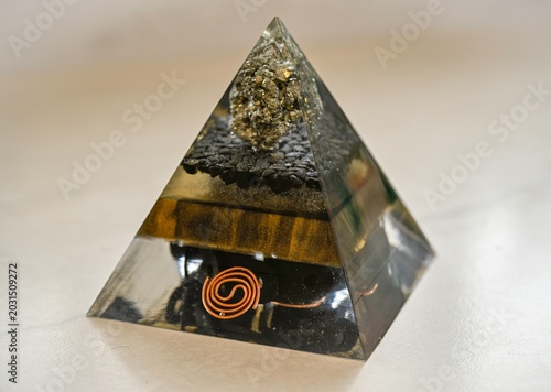 Handmade Orgone Pyramid with Pyrite Crystal and Obsidian Layers – Unique Black and Gold Energy Pyramid with Circular Metal Geometry, Close-Up Isolated on White Background