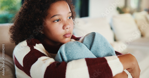 Photos Unhappy, child and thinking on sofa, home and girl with low self esteem from bullying and bad memory