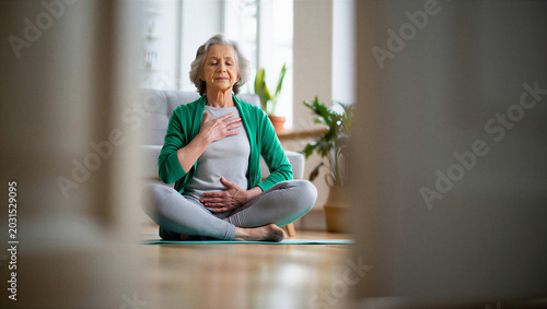 Senior woman performing self-guided diaphragmatic breathwork by tracking chest and belly movements in quiet domestic solitude.