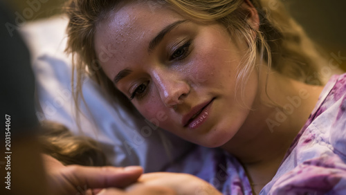 Labor and delivery nurse coaching a woman during childbirth in a hospital room late at night while providing support and guidance