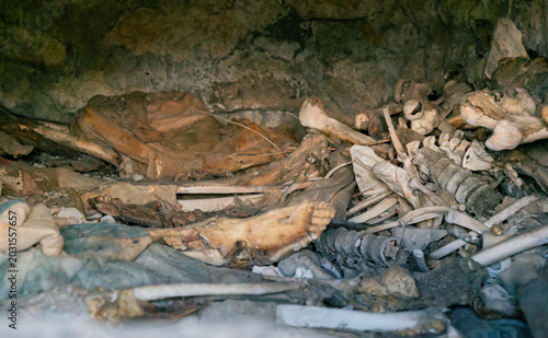 Interior view of an ancient Dargavs burial crypt, revealing human skeletal remains and deteriorated textiles