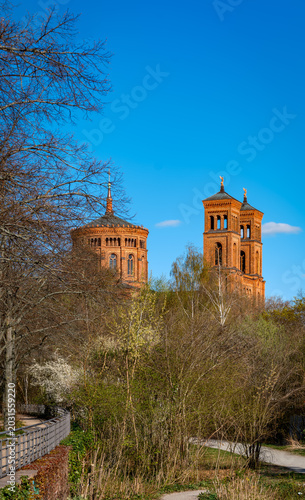 Wo früher die Berliner Mauer stand, blühen Frühlingsbäume am ehemaligen Luisenstädtischen Kanal vor den Türmen der denkmalgeschützten Kreuzberger Thomaskirche