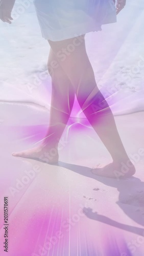 Vertical video: Sun urging bare feet walking shore, leaving prints while waves washing pink glow