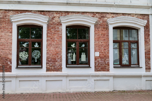 Tableau sur toile Three windows with brown frames on red brick building facade