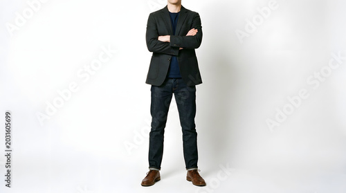 Man in a suit standing with arms crossed white background business attire