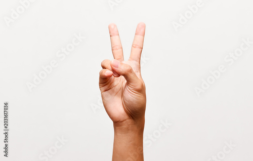 Close up of person showing peace sign or victory gesture with two fingers up on isolated white background.
