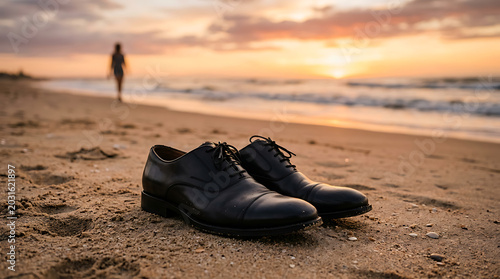 A moment of transition elegant shoes on the sand as a lone figure walks towards the serene ocean sunset