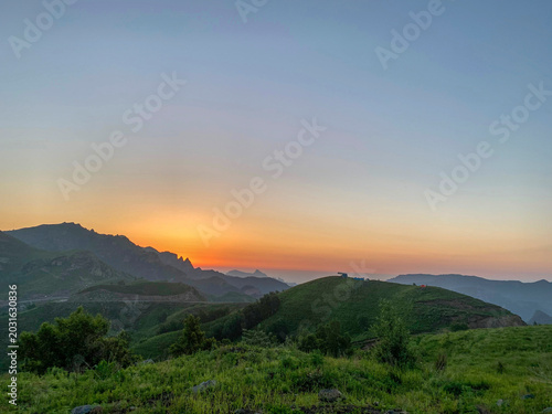 Bild auf Leinwand Beautiful sunset over rolling green hills and mountain ranges