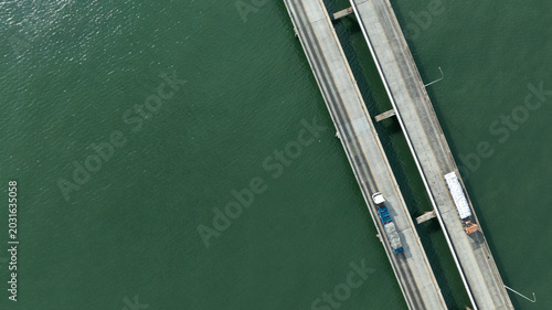 Aerial drone shot of container trucks driving to the port for cargo shipping.