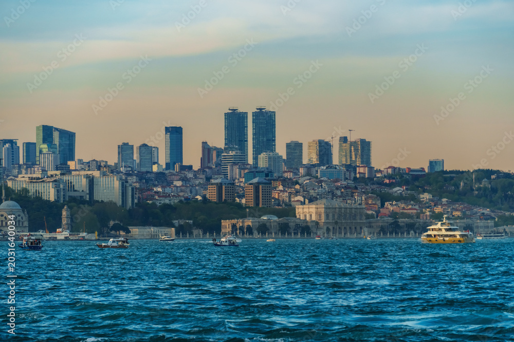 Obraz premium Panoramic View of the Istanbul City Skyline and Bosphorus Strait with Modern Skyscrapers, Traditional Architecture, and Boats Sailing on the Blue Sea at Sunset or Golden Hour