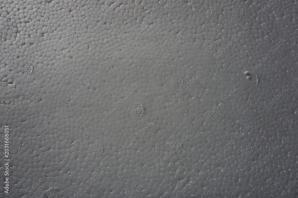 Obraz premium Macro shot of a white expanded polystyrene foam surface, showing the detailed cellular texture and structure. White plastic foam packaging material close-up.