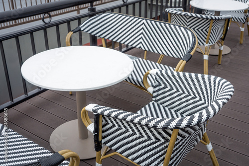Rattan frame chair woven from black and white artificial rattan and round white top stool tables.