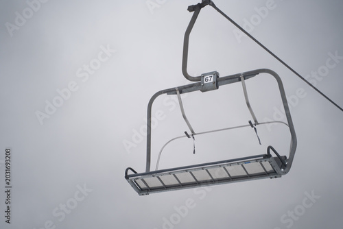 Photography Empty ski chairlift number 67 hanging against gray overcast sky