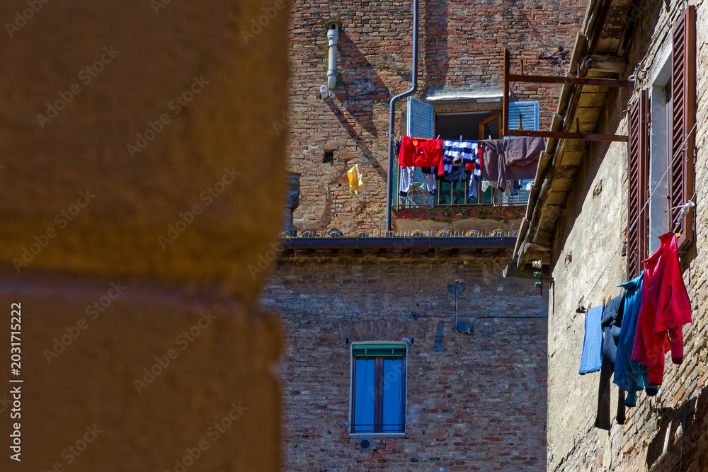 Naklejka premium Some laundry is drying on the balconies of the houses of city center of Siena, Italy