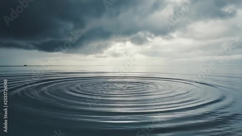 Ripples forming on the surface of calm grey ocean water under a cloudy sky for serenity and nature, water concept