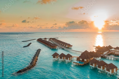Foto Overwater bungalows at sunset in tropical ocean paradise with overwater bungalow