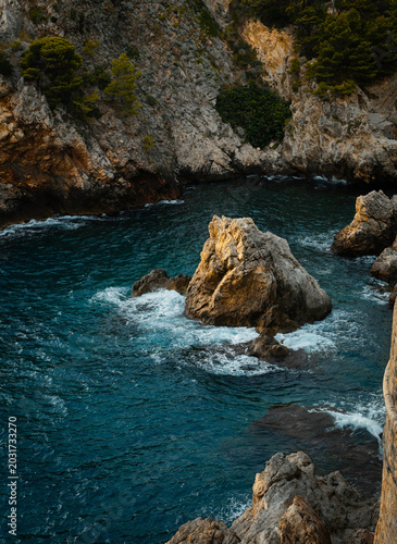 Obraz na plátně Deep blue Adriatic Sea crashing against rugged limestone cliffs and coastal rocks in Dalmatia