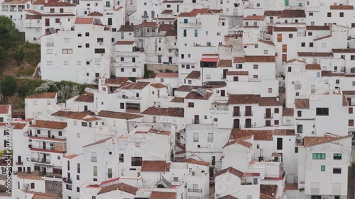 Aerial view of the traditional white houses and terracotta rooftops of a hillside village in Casares, Andalusia, Spain.