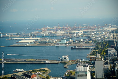 Tableau sur toile 晴れた日に広がる広大な港湾都市の眺め。多数のコンテナ船、クレーン、高層ビル、橋、道路が密集して配置されている。