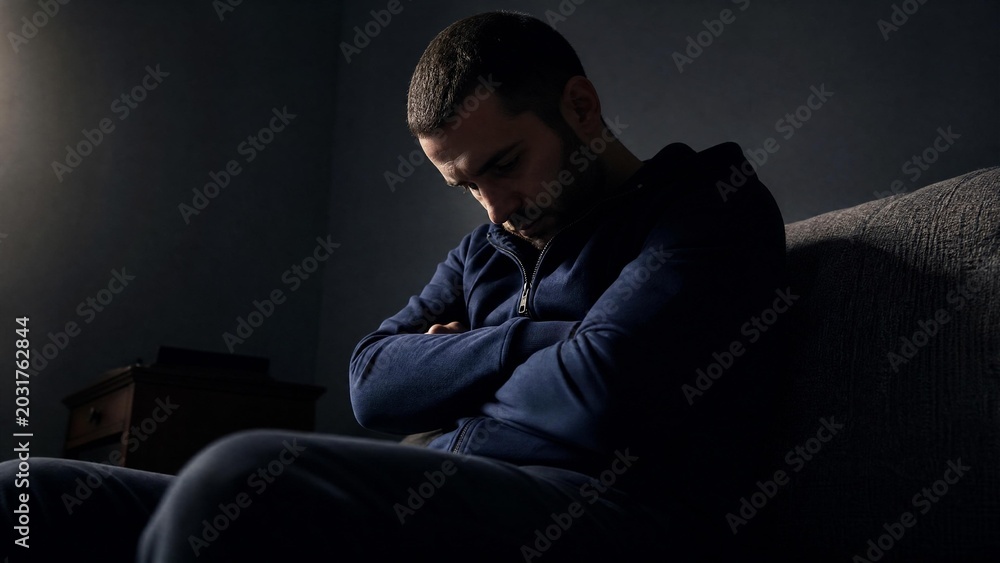 Fototapeta premium Depressed Man Sitting Alone in Dark Room Feeling Sad and Lonely