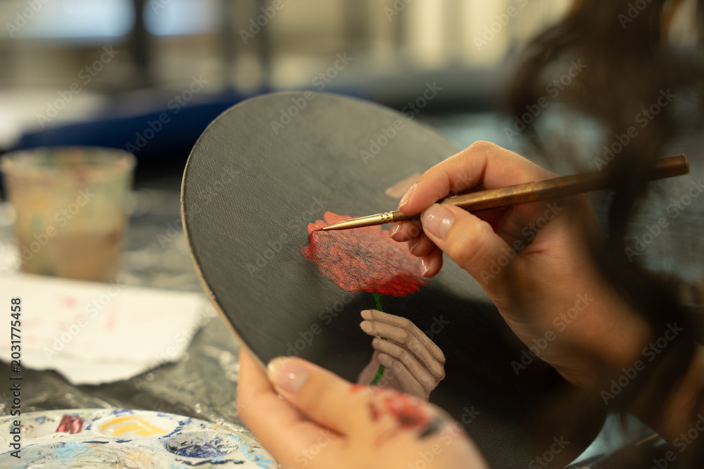 Obraz premium Artist hands painting red flower on canvas