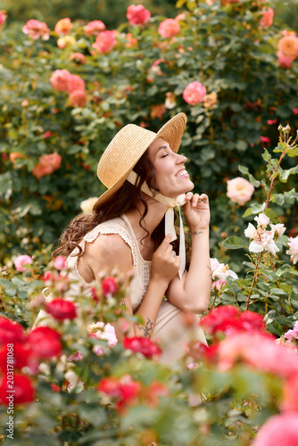 Joyful woman enjoying a sunny day in a vibrant rose garden full of colorful blooms