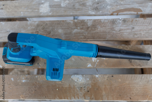 High angle top view of a blue battery operated leaf blower placed on a rustic wooden pallet structure
