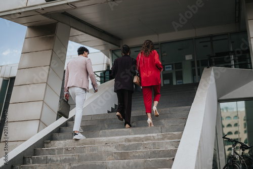 Tableau sur toile Three business professionals walk up outdoor steps toward a modern office entrance