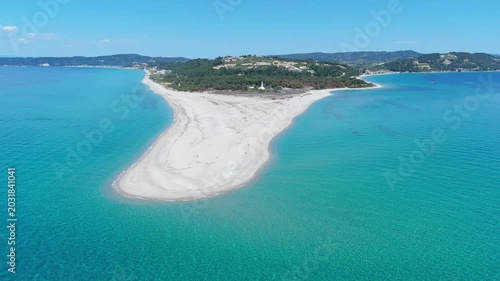 Aerial view of Possidi Beach sandy cape stretching into the turquoise Aegean Sea with lush green hills in the background under a clear blue sky Greece.