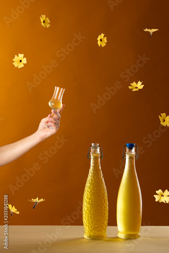 bottles of home made limonchello with hand raising a toast and yellow flowers