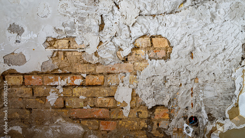 Foto Detailed view of a textured wall showing layers of plaster and exposed bricks in