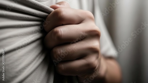 A close-up shot of a person's hand tightly gripping a grey fabric, conveying stress or anxiety.