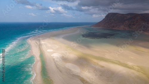 Bild auf Leinwand Aerial sandbar and turquoise lagoon by rocky coast