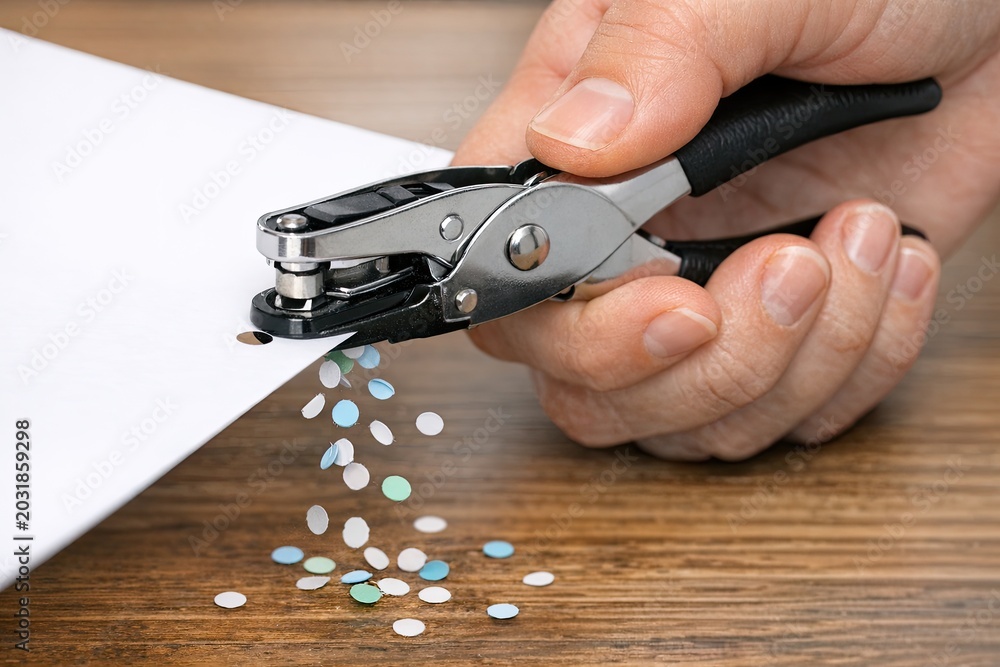 Fototapeta premium A person cutting a piece of paper with a pair of scissors, a simple office task